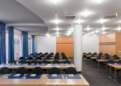 Ein Konferenzraum mit mehreren Reihen von Tischen und Stühlen ist für ein Meeting vorbereitet.