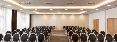 Ein moderner Meetingraum in Münster-Gütersloh mit Reihen schwarzer Stühle und einem Tisch vorne wartet auf Teilnehmer.