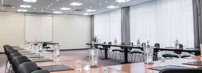 Ein moderner, leerer Konferenzraum mit Tischen in U-Form und Wasserflaschen wartet auf ein Meeting.