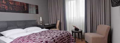 Ein Superior-Zimmer mit einem großen Bett, moderner Einrichtung und einem gemütlichen Sessel neben einem Tisch.