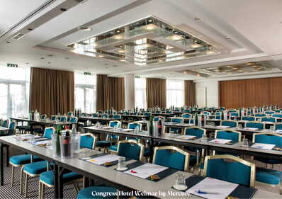 Ein großer Konferenzraum mit vielen Tischen und Stühlen ist für eine Veranstaltung im Congress Hotel vorbereitet.