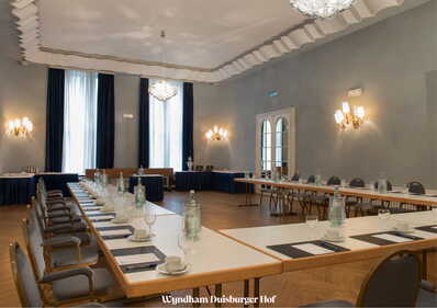 Ein eleganter Konferenzraum mit gedecktem Tisch, bereit für ein Meeting im Wyndham Duisburger Hof.