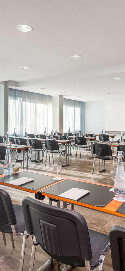 Ein heller Seminarraum in Wittenberg ist mit Tischen, Stühlen und Schreibmaterialien für eine Schulveranstaltung vorbereitet.