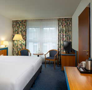 Ein elegantes Hotelzimmer mit einem großen Bett, einem kleinen Tisch und gemütlicher Beleuchtung strahlt Komfort aus.