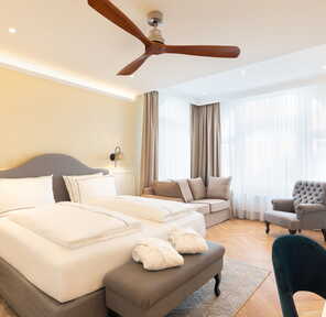 Eine elegante Junior Suite mit Doppelbett, Sofa und Sessel bietet komfortable Unterkunft in einem stilvollen Ambiente.