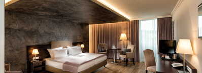 Ein Deluxe-Zimmer mit einem großen Bett, elegantem Holzboden und stilvoller Beleuchtung schafft eine luxuriöse Atmosphäre.