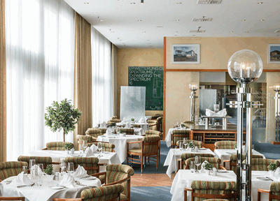 Elegantes Restaurant mit gedeckten Tischen und großen Fenstern, das eine einladende Atmosphäre schafft.