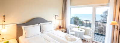 Ein luxuriöses Hotelzimmer mit Doppelbett bietet einen atemberaubenden Meerblick und einen Balkon für entspannte Momente.