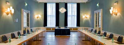 Ein eleganter Konferenzraum mit U-förmiger Tischanordnung, bereit für ein Meeting, in der DUI21-Konferenz.