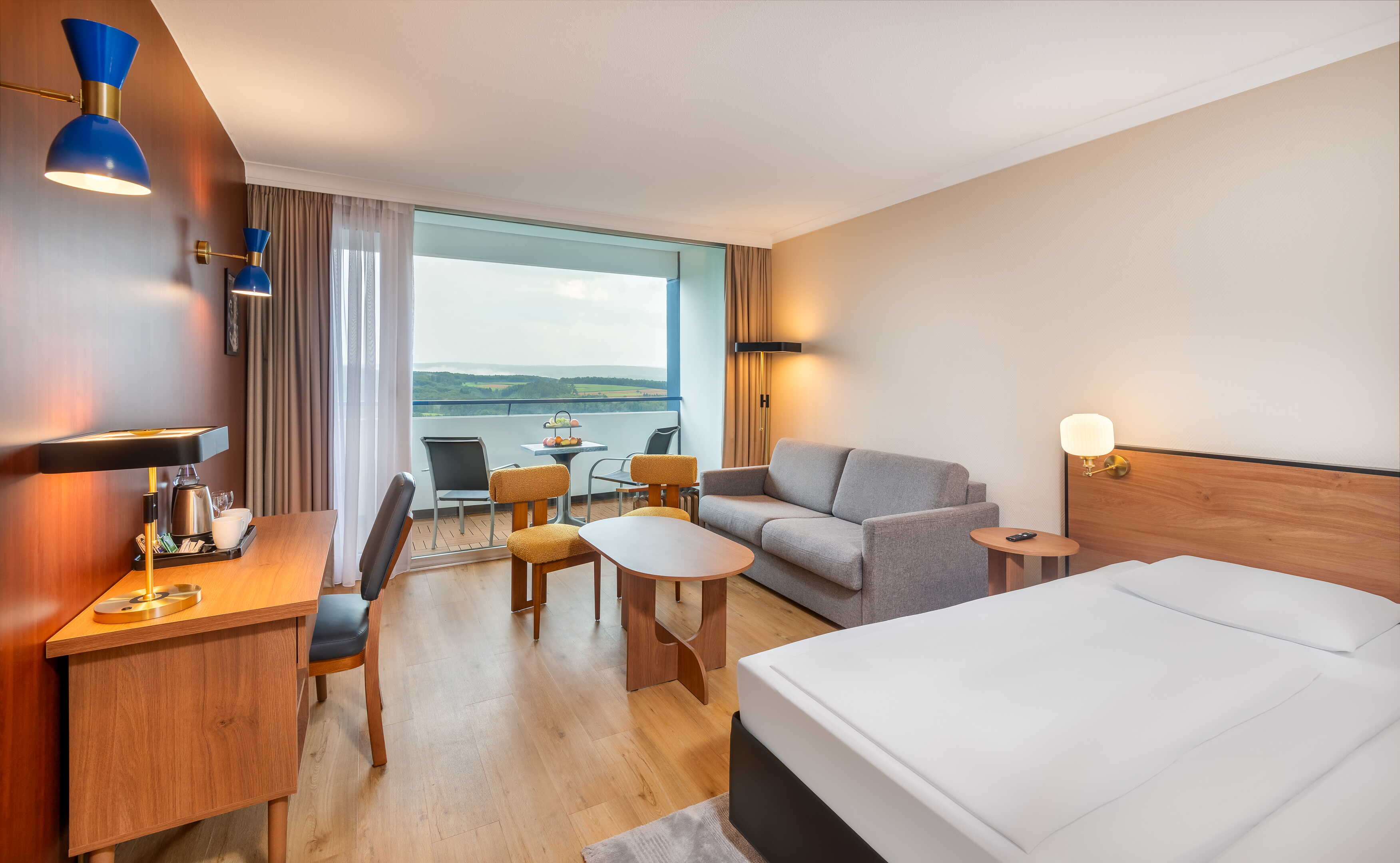 Ein stilvolles Hotelzimmer mit modernem Interieur, einem Schreibtisch und einem Balkon mit Blick auf die Landschaft.