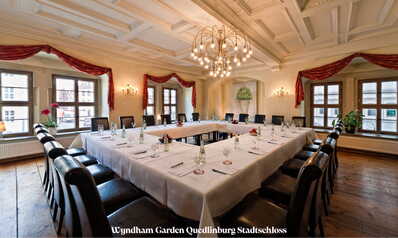 Ein elegant dekorierter Konferenzraum mit U-förmigem Tisch, gedeckt mit Gläsern und Wasserflaschen, im Stadtschloss.