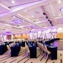 A spacious, elegantly lit conference room with rows of tables and chairs is set up for a large meeting.