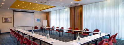 Ein Konferenzraum in Wismar mit U-förmiger Tischanordnung, Stühlen und Präsentationsausstattung.