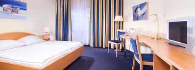 Ein gemütliches Hotelzimmer mit Bett, Schreibtisch und blauen Vorhängen, das eine einladende Atmosphäre schafft.