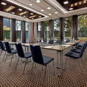 A modern meeting room features U-shaped tables and elegant blue chairs, creating an inviting space for discussions.