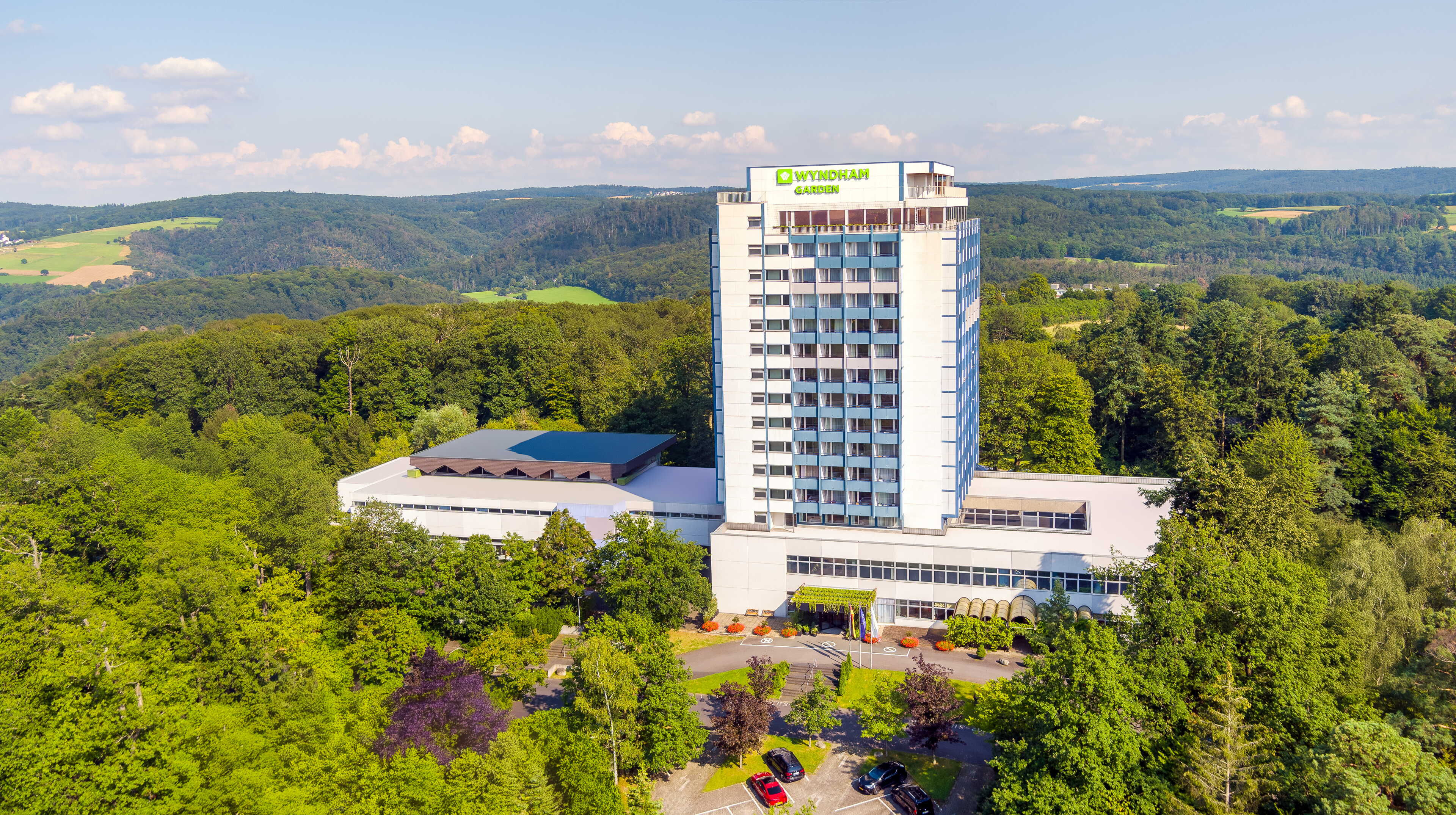 Ein hohes Hotelgebäude ragt aus einem üppigen Waldgebiet in einer malerischen Landschaft hervor.