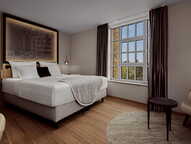 Elegantes Schlafzimmer mit großem Bett und Wandkunst, das durch ein großes Fenster mit Vorhängen beleuchtet wird.