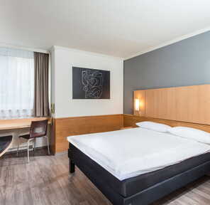 Ein modernes Einzelzimmer mit einem gemütlichen Bett, Schreibtisch und stilvoller Kunst an der Wand.