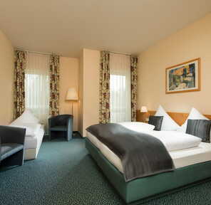 Ein elegantes Doppelzimmer in der Residenz mit gemütlichem Bett, modernen Sesseln und stilvoller Dekoration.