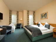 A spacious double room features a large bed, modern decor, and comfortable seating, perfect for a relaxing stay at the Residenz.