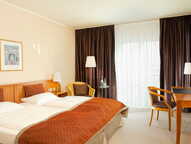 Ein gemütliches Doppelzimmer mit einem großen Bett, Schreibtisch und zwei Stühlen, ideal für einen angenehmen Aufenthalt.