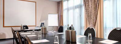 Ein moderner Konferenzraum mit einem langen Tisch, Stühlen, Notizblöcken und Wasserflaschen wartet auf ein Meeting.