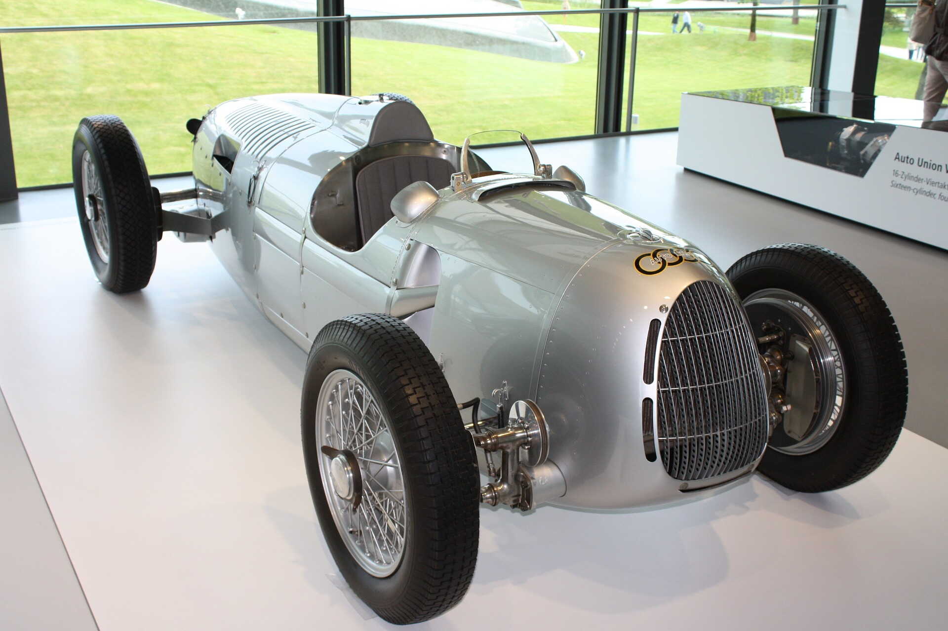 Ein silberner Oldtimer-Rennwagen steht in einem modernen Ausstellungsraum der Autostadt Wolfsburg.