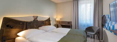 Gemütliches Doppelzimmer mit modernem Dekor, einem großen Bett und einem Schreibtisch neben dem Fenster.