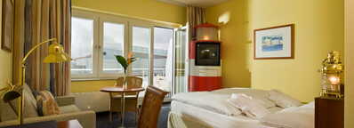 Ein gemütliches Standardzimmer mit gelben Wänden, einem Doppelbett, Schreibtisch und einem kleinen Tisch am Fenster.