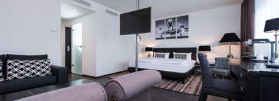 Elegante Hotelsuite mit modernem Dekor, einem großen Bett, Schreibtisch und gemütlicher Sitzecke, die Komfort bietet.