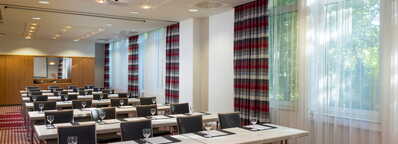 Ein heller Konferenzraum mit Tischen und Stühlen ist für ein Meeting im Rhein-Main-Gebiet vorbereitet.