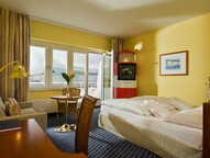 A cozy standard room features a neatly made bed, a small dining table, and a vintage TV cabinet, all under soft lighting.