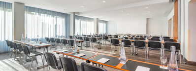 Ein heller Seminarraum in Wittenberg ist mit Tischen, Stühlen und Schreibmaterialien für eine Schulveranstaltung vorbereitet.