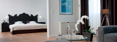 Ein stilvoll eingerichtetes Schlafzimmer mit großem Bett und gemütlicher Sitzecke lädt zum Entspannen in der Suite ein.