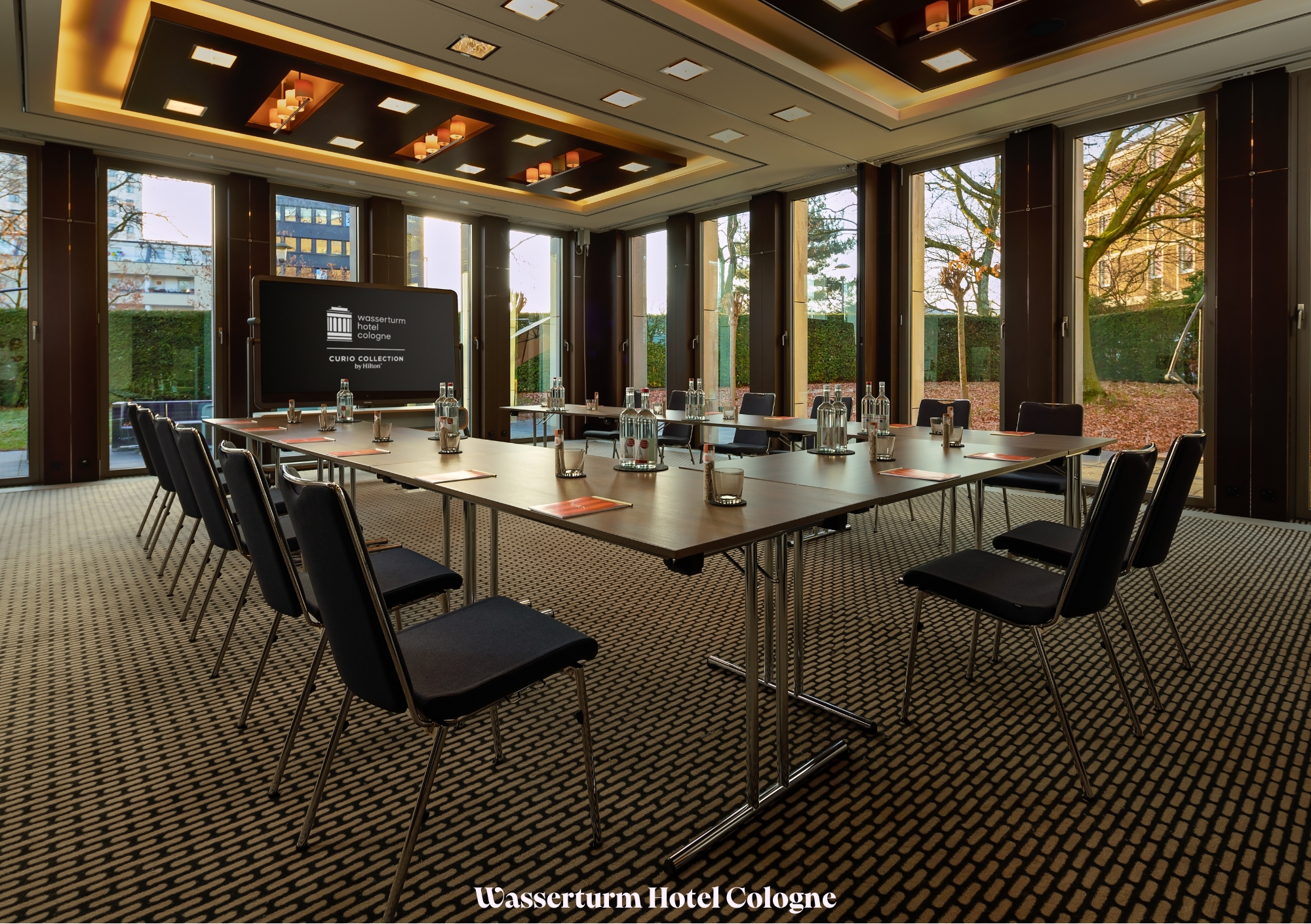 Ein Konferenzraum im Wasserturm Hotel Köln ist für ein Meeting vorbereitet, mit Stühlen und Wasserflaschen auf dem Tisch.